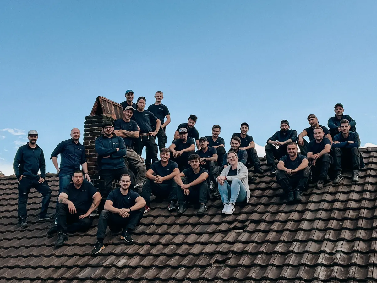 Das Team von Bähren Bedachungen sitzt gemeinsam auf einem Ziegeldach